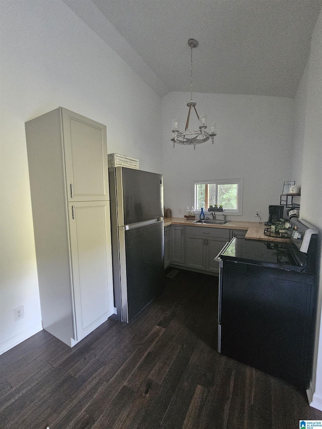 kitchen with pendant lighting, stainless steel fridge, dark hardwood / wood-style flooring, vaulted ceiling, and kitchen peninsula