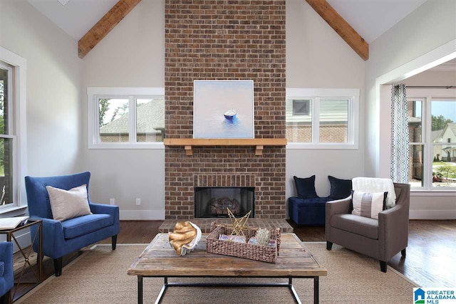 living room with dark wood-type flooring, beamed ceiling, a brick fireplace, and plenty of natural light