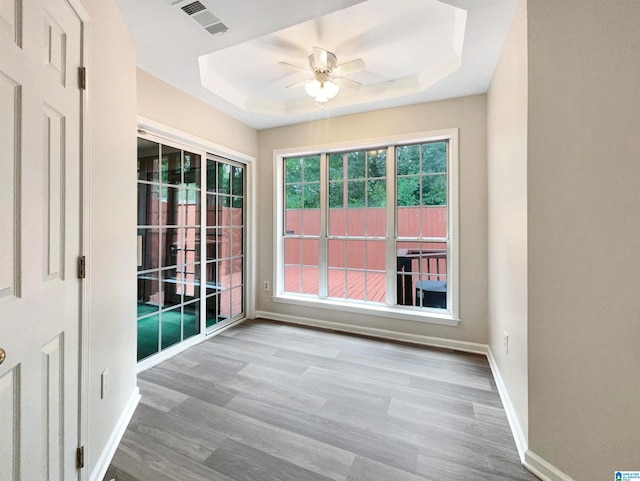 unfurnished room with wood-type flooring, a raised ceiling, and ceiling fan