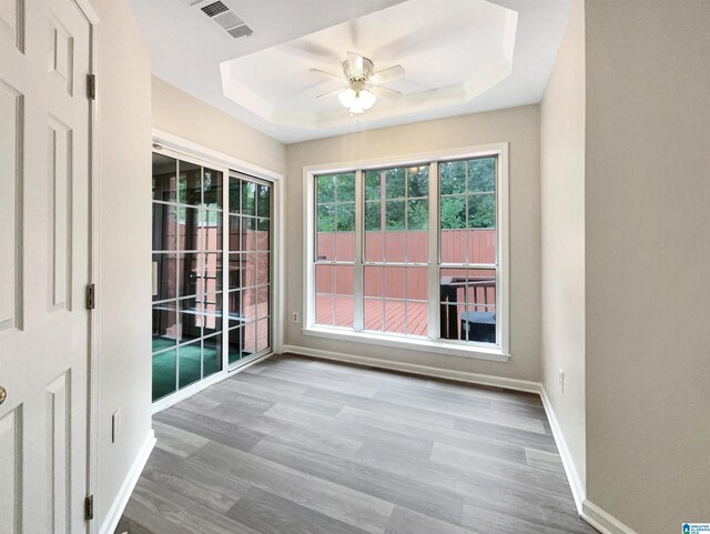 empty room with wood-type flooring, ceiling fan, and a tray ceiling