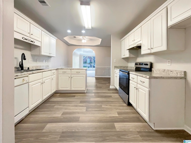 kitchen featuring stainless steel electric range, white cabinetry, a tray ceiling, dishwasher, and light hardwood / wood-style floors