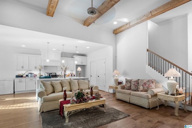 living room featuring beamed ceiling, wood-type flooring, sink, ornamental molding, and ceiling fan