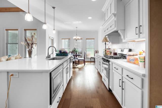 kitchen with sink, decorative light fixtures, a center island with sink, stainless steel appliances, and white cabinets