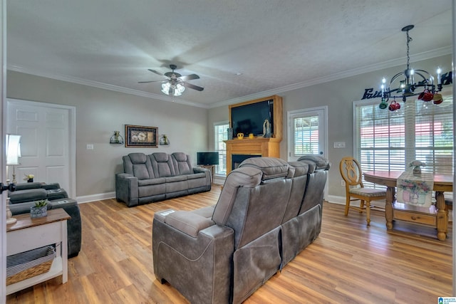 living room featuring hardwood / wood-style floors, ceiling fan with notable chandelier, ornamental molding, and a textured ceiling