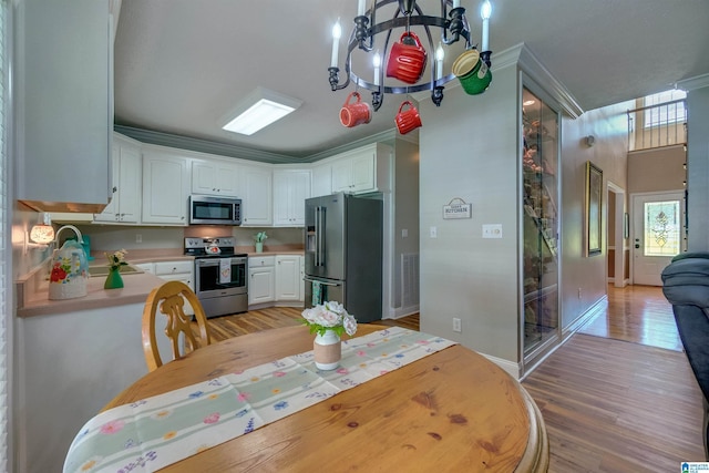 kitchen featuring appliances with stainless steel finishes, sink, white cabinets, and light hardwood / wood-style flooring