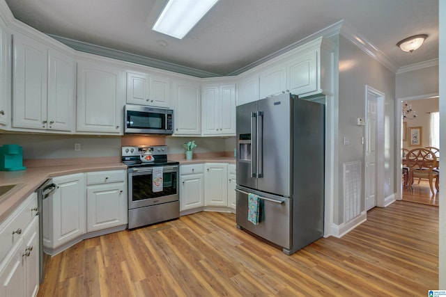 kitchen with stainless steel appliances, crown molding, white cabinets, and light hardwood / wood-style flooring