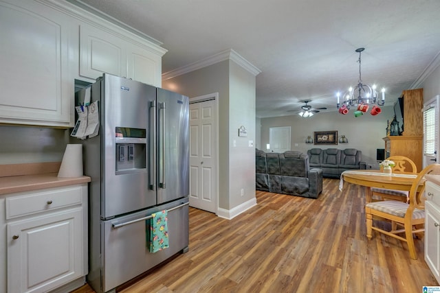 kitchen featuring crown molding, stainless steel fridge, white cabinets, decorative light fixtures, and light wood-type flooring