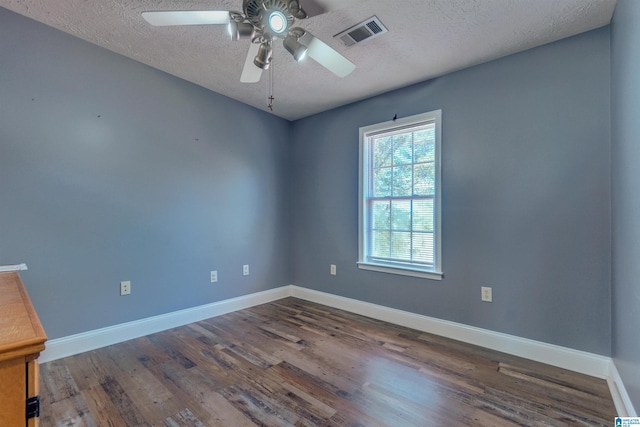 spare room featuring dark hardwood / wood-style flooring, ceiling fan, and a textured ceiling