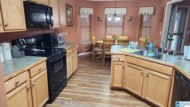 kitchen with black appliances, light brown cabinetry, sink, hanging light fixtures, and light hardwood / wood-style flooring