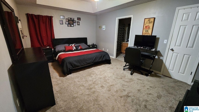 carpeted bedroom with connected bathroom and a raised ceiling