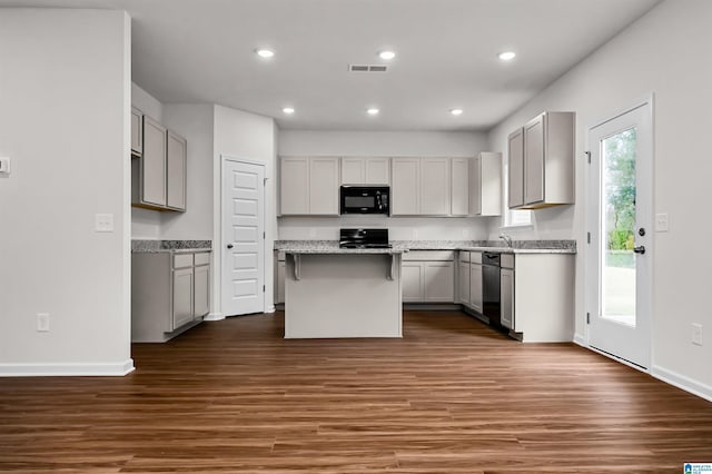 kitchen with gray cabinetry, black appliances, dark hardwood / wood-style floors, and a kitchen island