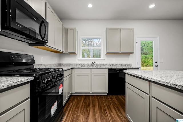 kitchen with light stone counters, dark wood-type flooring, black appliances, and gray cabinets