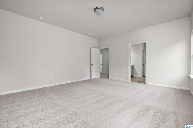 unfurnished bedroom featuring ensuite bath and light colored carpet