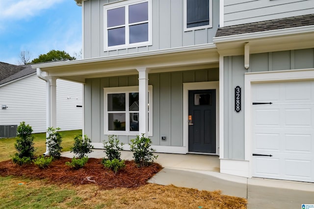 doorway to property with cooling unit, a garage, and covered porch