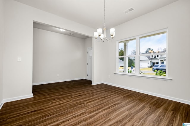 empty room featuring dark wood-type flooring and a notable chandelier