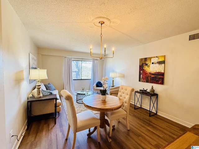 dining space featuring a textured ceiling, a notable chandelier, and wood-type flooring