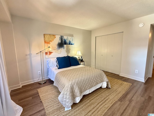 bedroom with a textured ceiling, dark wood-type flooring, and a closet