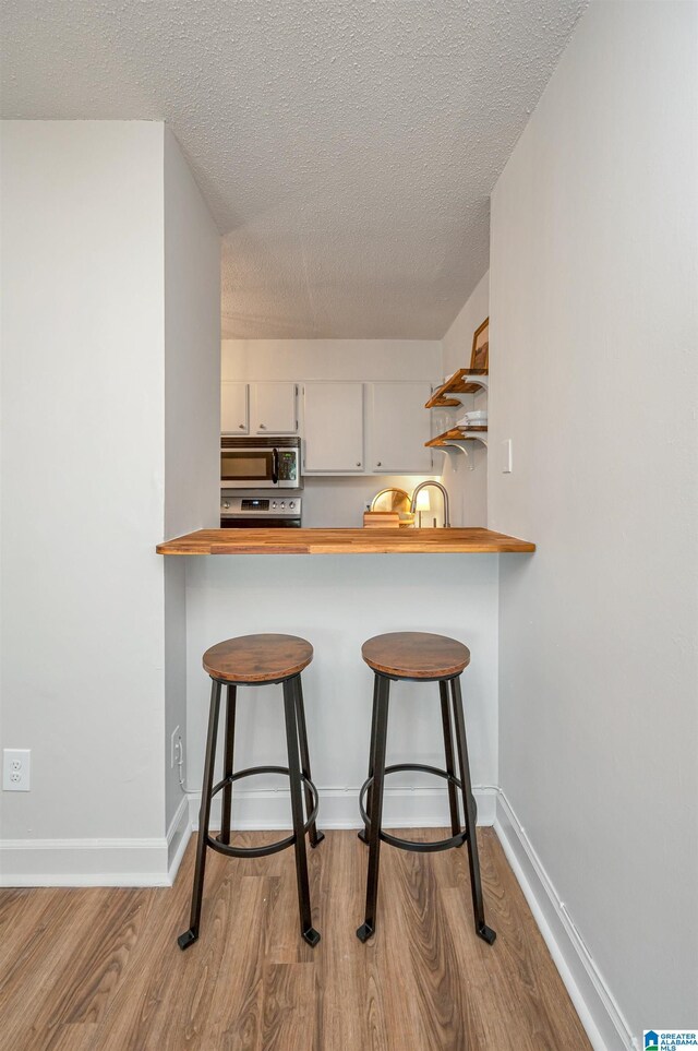 kitchen with white cabinetry, sink, appliances with stainless steel finishes, wood counters, and gray cabinetry