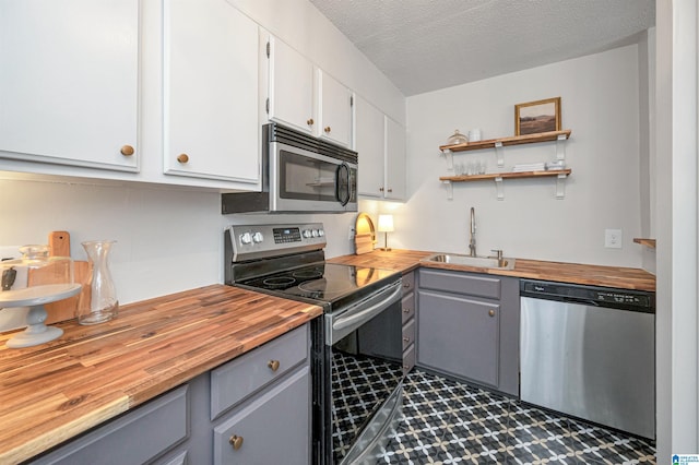 kitchen with sink, gray cabinets, stainless steel appliances, and wood counters