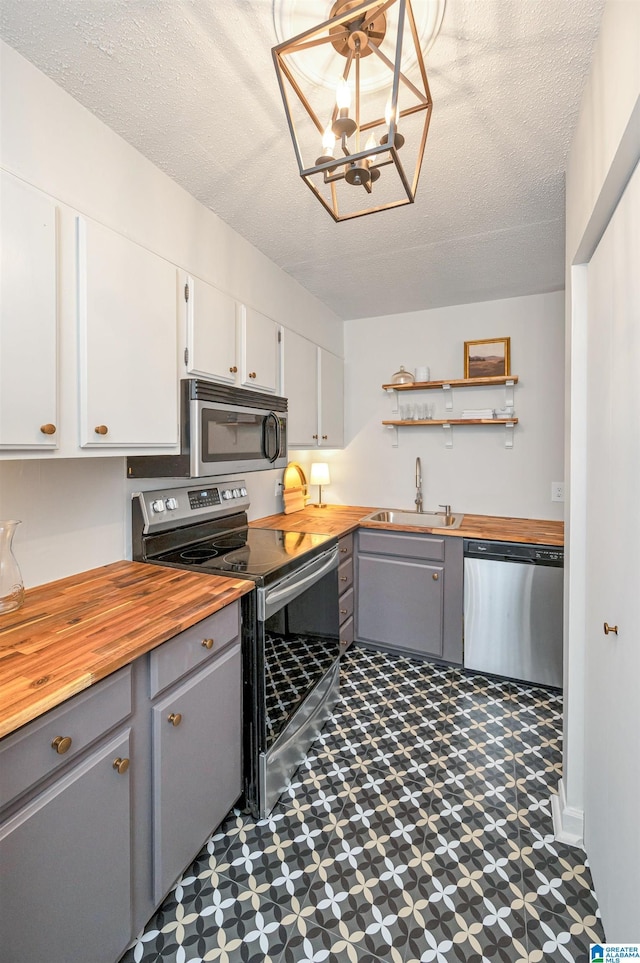 kitchen with appliances with stainless steel finishes, sink, wooden counters, white cabinetry, and gray cabinetry