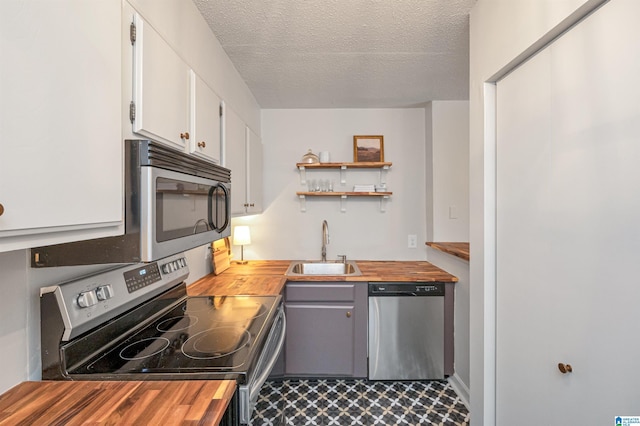 kitchen featuring butcher block countertops, stainless steel appliances, and white cabinetry