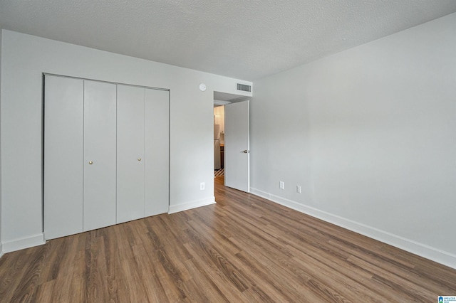 unfurnished bedroom featuring a textured ceiling, hardwood / wood-style flooring, and a closet