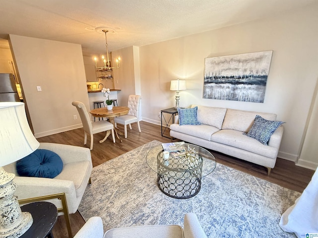 living room featuring an inviting chandelier, dark hardwood / wood-style flooring, and a textured ceiling