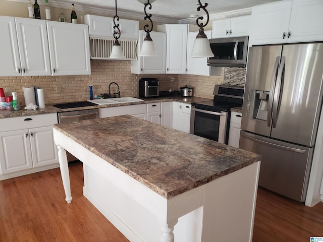 kitchen with a kitchen island, sink, white cabinetry, hanging light fixtures, and stainless steel appliances