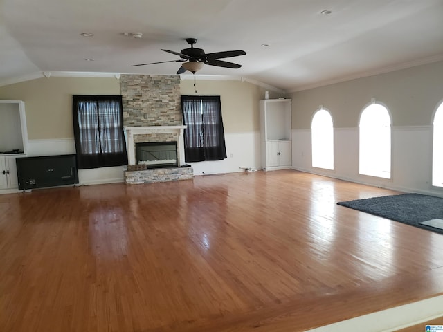 unfurnished living room with ceiling fan, a fireplace, vaulted ceiling, ornamental molding, and light hardwood / wood-style flooring