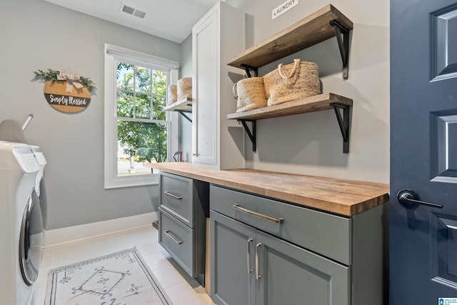 clothes washing area featuring cabinets, separate washer and dryer, and light tile patterned floors