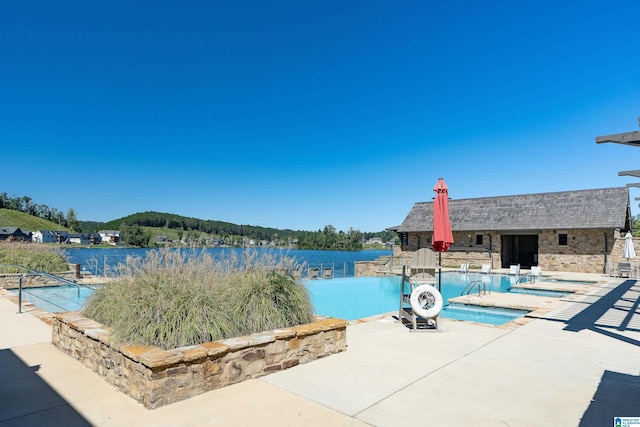 view of swimming pool with a water view and a patio