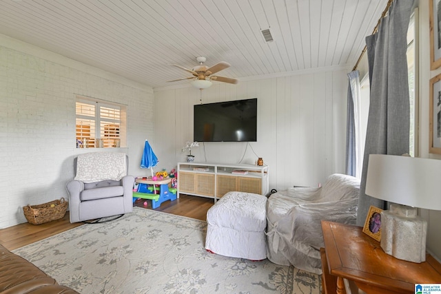 living room featuring wood ceiling, hardwood / wood-style flooring, ceiling fan, and brick wall