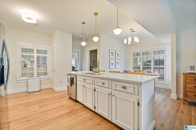 kitchen with a center island with sink, light wood-type flooring, hanging light fixtures, dishwasher, and white cabinets