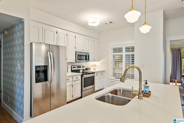 kitchen featuring sink, hanging light fixtures, appliances with stainless steel finishes, decorative backsplash, and white cabinets