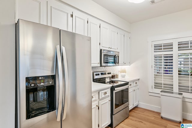 kitchen with stainless steel appliances, white cabinetry, tasteful backsplash, and light wood-type flooring