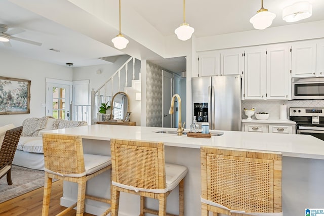 kitchen with pendant lighting, light hardwood / wood-style flooring, a breakfast bar, stainless steel appliances, and decorative backsplash