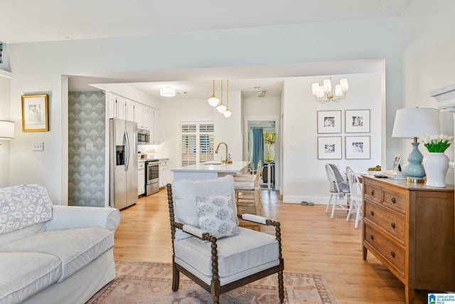 living room with an inviting chandelier, sink, and light hardwood / wood-style floors