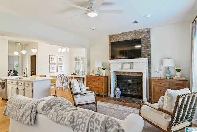 living room with a brick fireplace, sink, plenty of natural light, and light hardwood / wood-style flooring