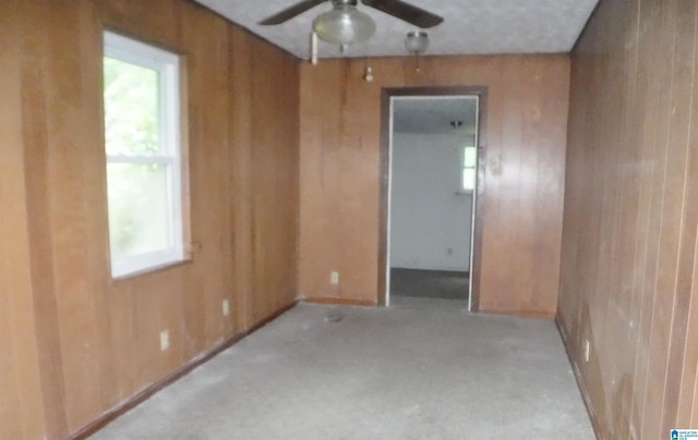 spare room featuring ceiling fan and wood walls