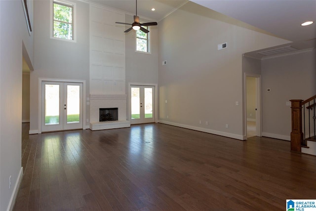 unfurnished living room featuring a towering ceiling, ornamental molding, and french doors