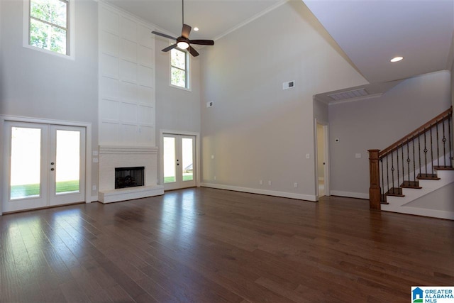 unfurnished living room featuring a towering ceiling, ornamental molding, french doors, and ceiling fan