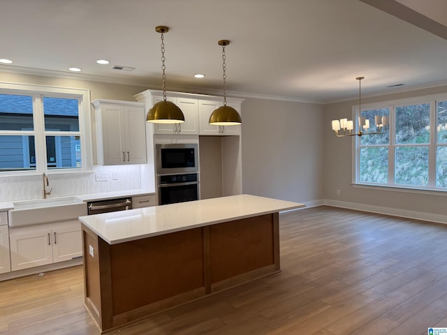 kitchen featuring white cabinetry, a center island, pendant lighting, stainless steel appliances, and backsplash