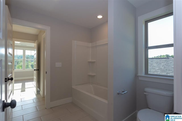 bathroom with tile patterned flooring, bathing tub / shower combination, and toilet