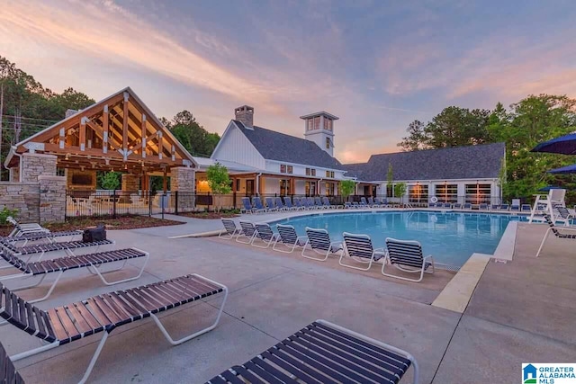 pool at dusk featuring a gazebo and a patio