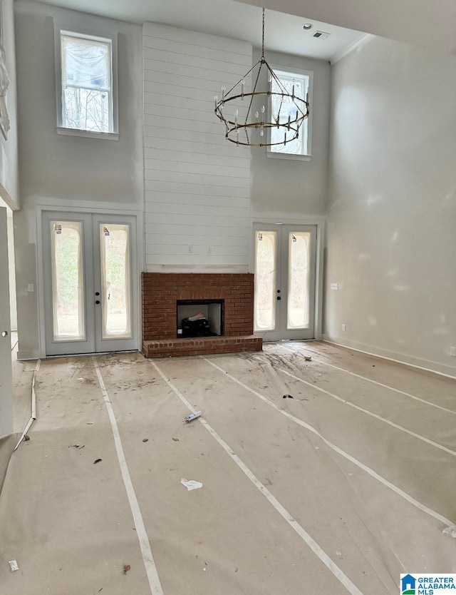 unfurnished living room with french doors, a chandelier, and a high ceiling