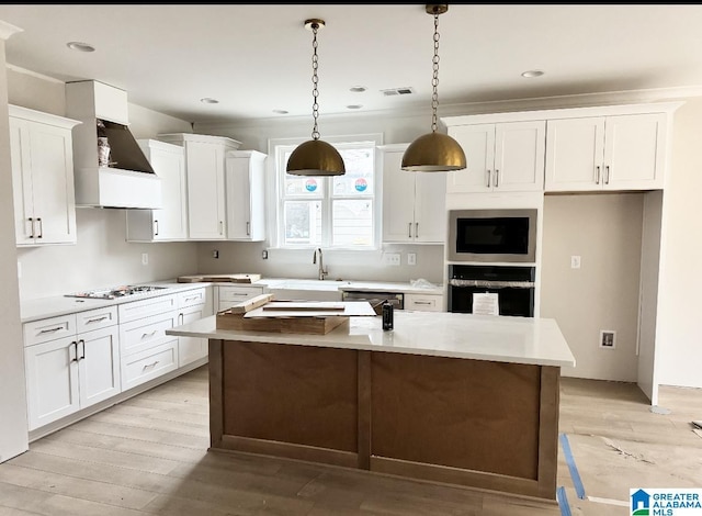 kitchen with white cabinetry, a center island, oven, and decorative light fixtures