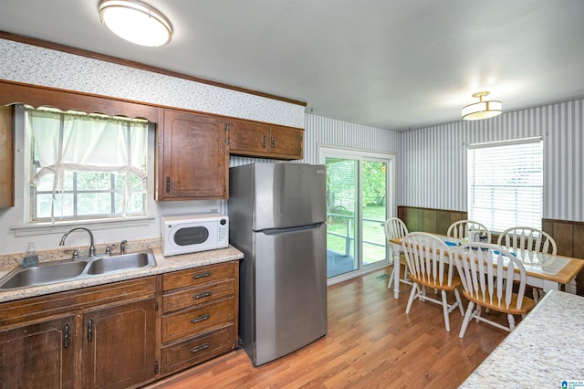 kitchen featuring stainless steel fridge, sink, and light hardwood / wood-style flooring