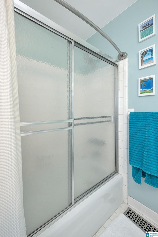 bathroom featuring tile patterned flooring and combined bath / shower with glass door