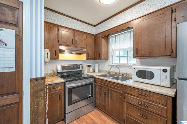 kitchen featuring stainless steel appliances, ornamental molding, sink, and light wood-type flooring