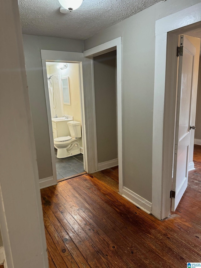 corridor featuring dark hardwood / wood-style flooring and a textured ceiling